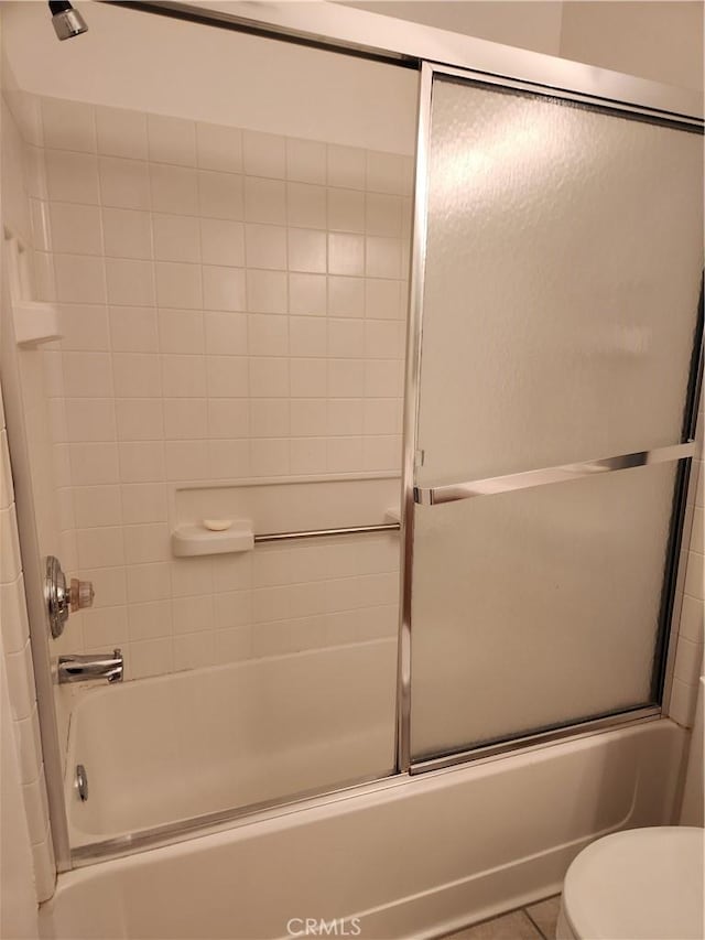 bathroom with toilet, tile patterned floors, and enclosed tub / shower combo