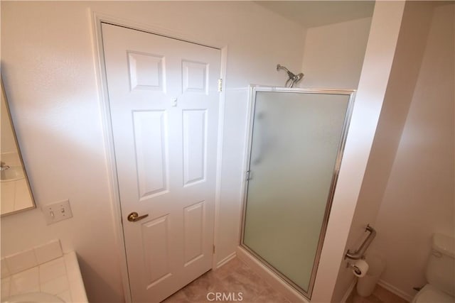 bathroom featuring a shower with shower door, tile patterned floors, and toilet