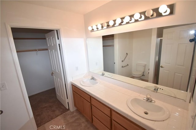 bathroom with toilet, vanity, and a shower with door