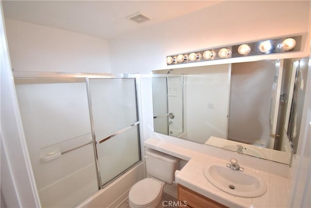 full bathroom featuring toilet, vanity, and combined bath / shower with glass door