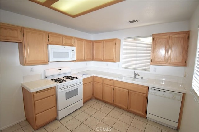 kitchen featuring sink, white appliances, tile counters, and a wealth of natural light