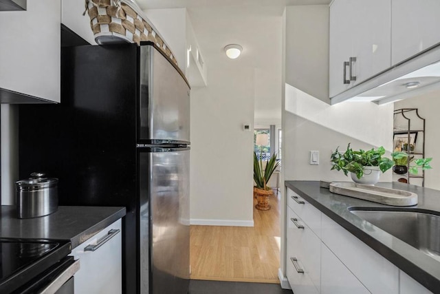 kitchen featuring white cabinets, stainless steel fridge, and hardwood / wood-style flooring