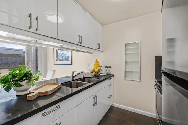 kitchen with dark tile patterned floors, plenty of natural light, sink, and white cabinetry