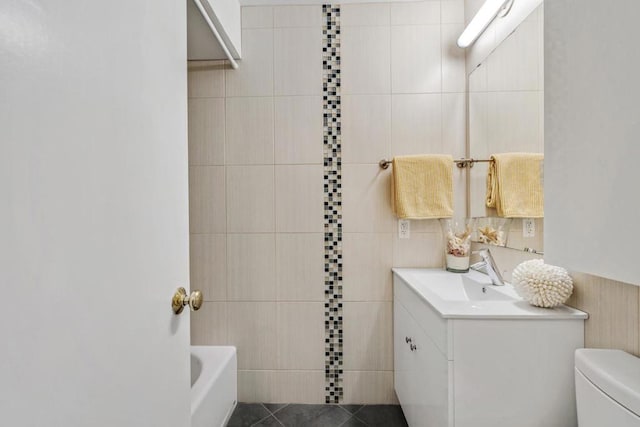 bathroom with toilet, vanity, tile walls, tile patterned floors, and a bathtub