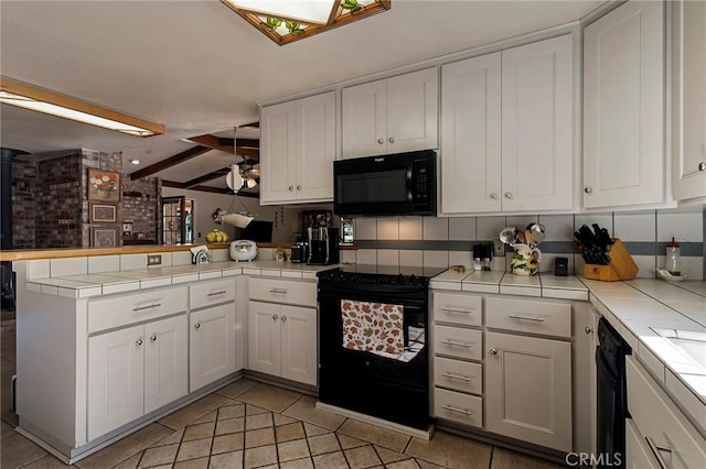 kitchen featuring white cabinetry, vaulted ceiling with beams, kitchen peninsula, tile countertops, and black appliances