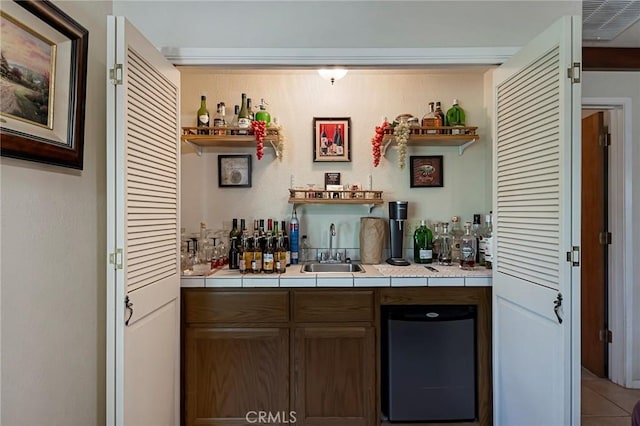 bar with tile patterned floors, tile counters, and sink