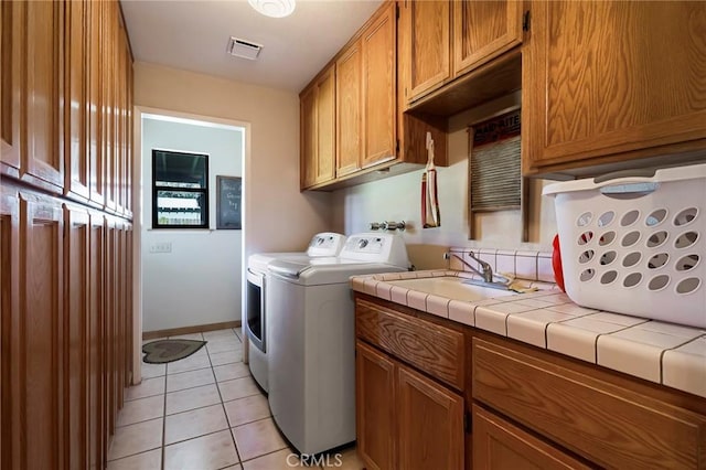 laundry area featuring washer and dryer, cabinets, light tile patterned floors, and sink