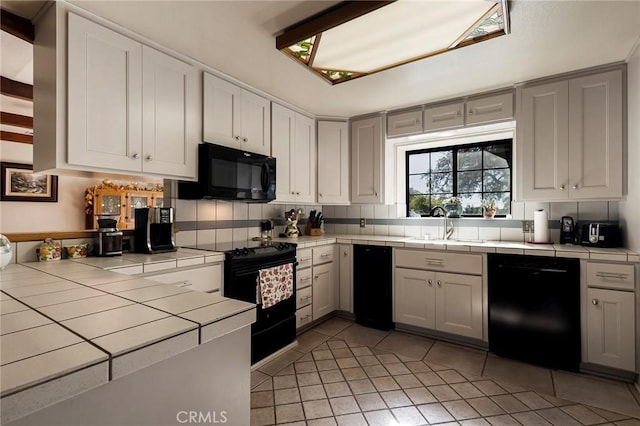 kitchen featuring black appliances, tile counters, sink, and backsplash