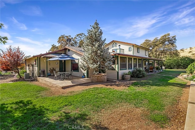 rear view of property with a lawn, a sunroom, cooling unit, and a patio