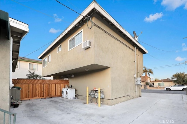 back of property featuring washer / clothes dryer and an AC wall unit