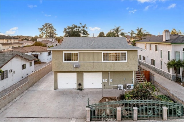 rear view of property featuring a wall mounted air conditioner, ac unit, and a garage