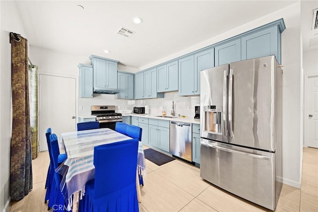 kitchen with sink, light tile patterned floors, stainless steel appliances, and blue cabinets