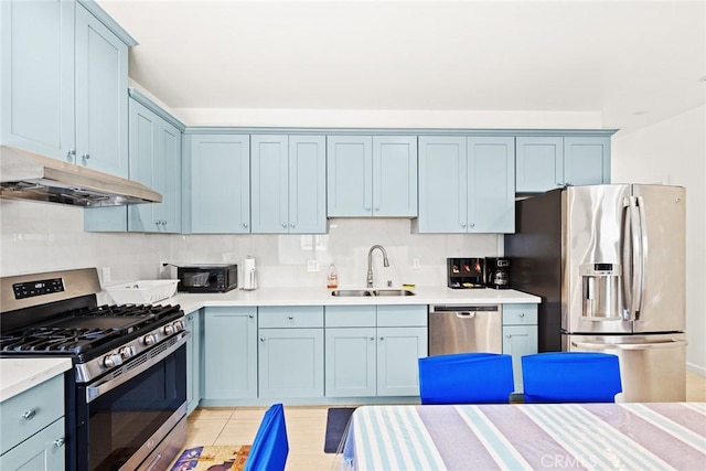 kitchen with sink, blue cabinetry, tasteful backsplash, light tile patterned flooring, and stainless steel appliances