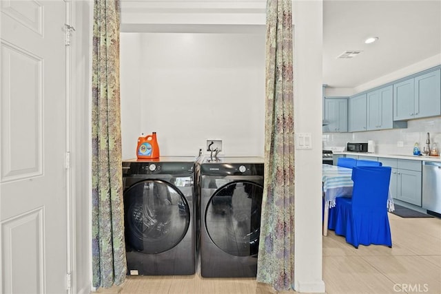 clothes washing area with washer and dryer, light tile patterned floors, and sink