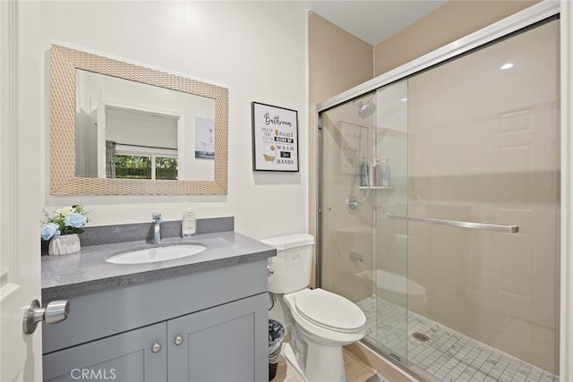 bathroom featuring a shower with door, vanity, and toilet