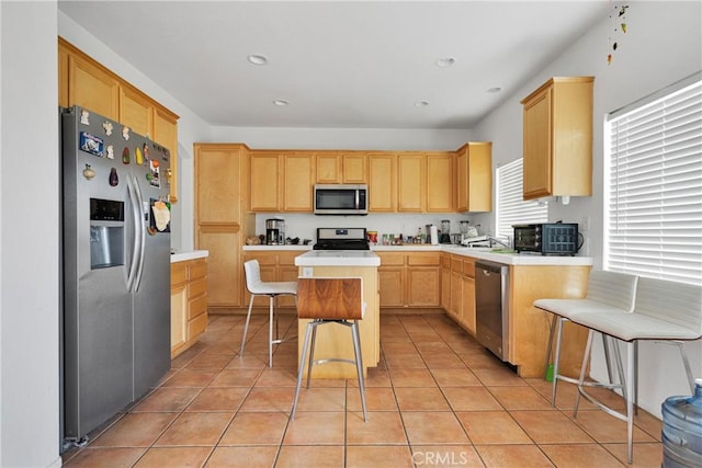 kitchen with a kitchen breakfast bar, a kitchen island, light tile patterned floors, and stainless steel appliances