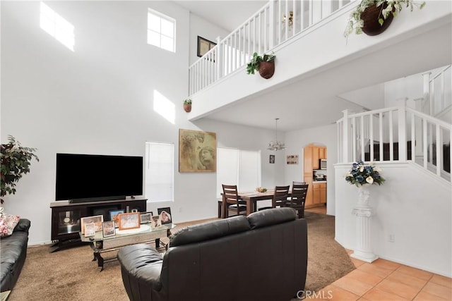 living room featuring carpet flooring, a high ceiling, and an inviting chandelier