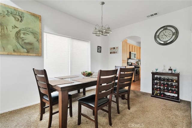 dining space featuring a notable chandelier and light colored carpet