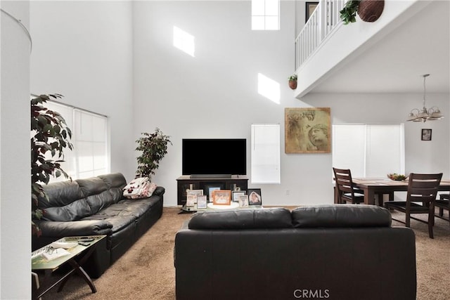 carpeted living room featuring a towering ceiling and a chandelier