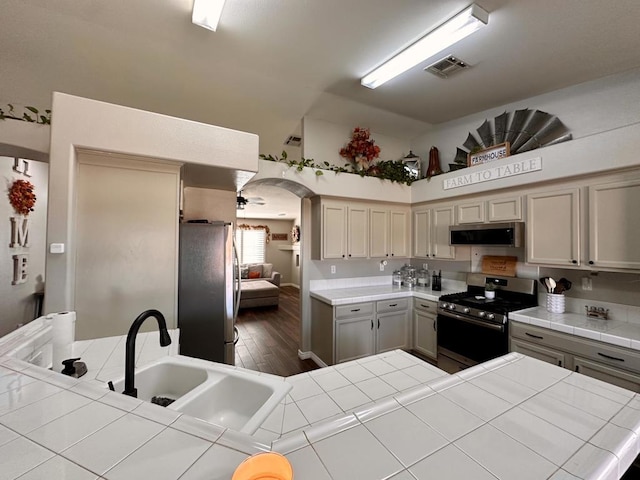 kitchen with tile countertops, dark hardwood / wood-style floors, sink, and stainless steel appliances