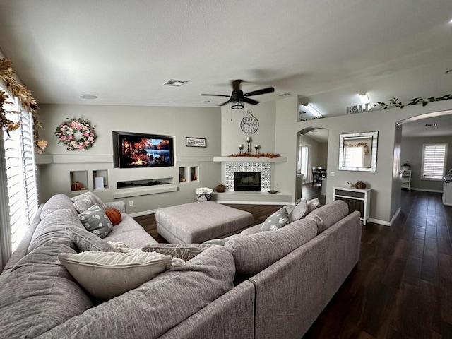 living room featuring a fireplace, ceiling fan, lofted ceiling, and dark wood-type flooring