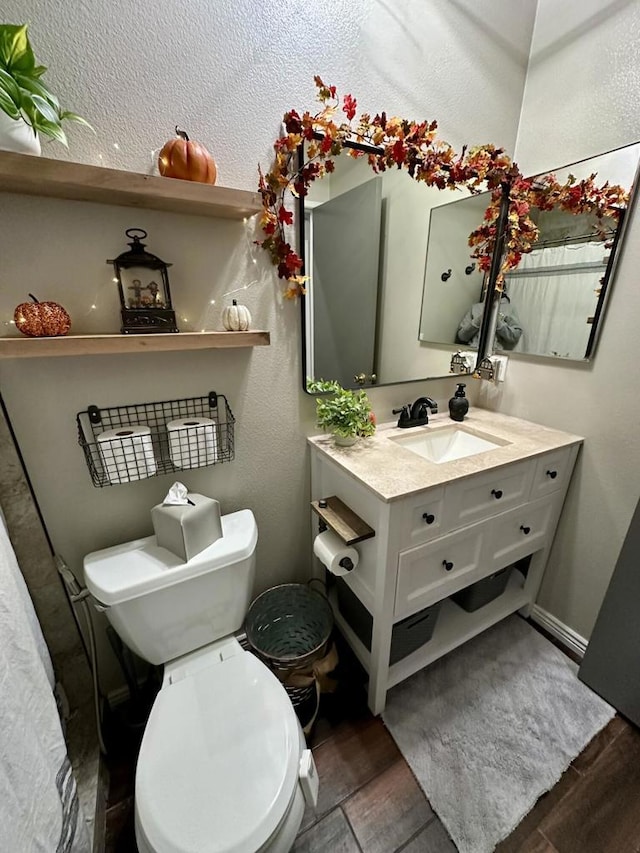 bathroom with toilet, vanity, and hardwood / wood-style flooring