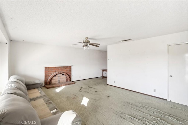 unfurnished living room featuring a textured ceiling, light colored carpet, a brick fireplace, and ceiling fan