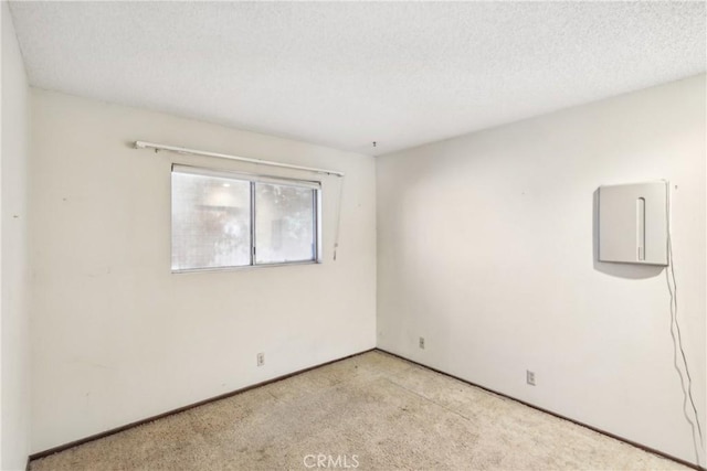 empty room with a textured ceiling and light colored carpet