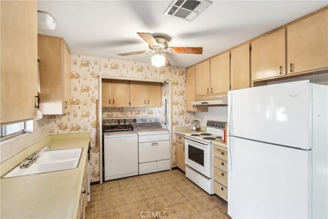 kitchen with light brown cabinetry, white appliances, washer and clothes dryer, and sink