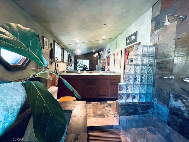 bathroom with vanity, vaulted ceiling, and tiled shower