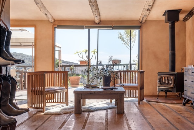 sunroom / solarium with beamed ceiling, a mountain view, and a wood stove