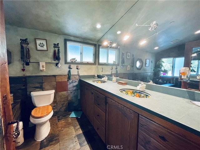 bathroom with vanity, toilet, tile walls, and vaulted ceiling