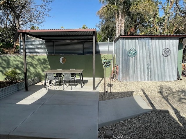 view of patio with a storage shed, an outdoor structure, outdoor dining area, and fence