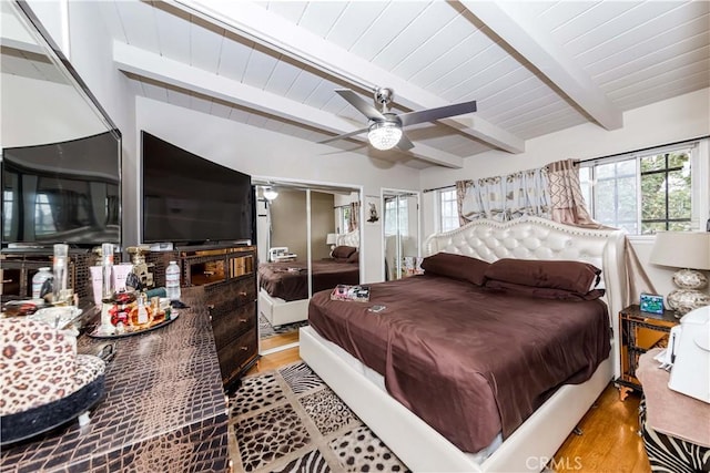 bedroom with multiple windows, beam ceiling, and light hardwood / wood-style floors