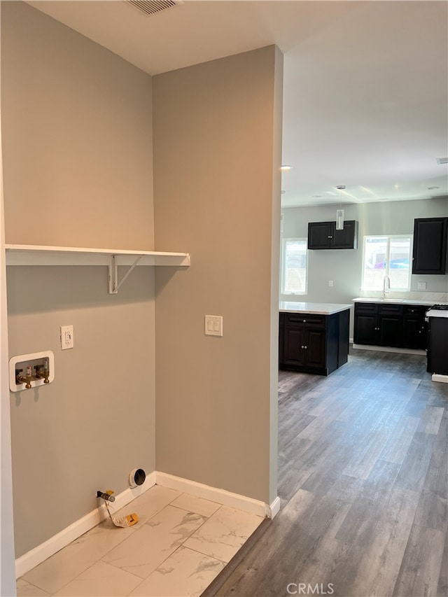 washroom with hookup for a washing machine, hookup for a gas dryer, sink, and light hardwood / wood-style flooring