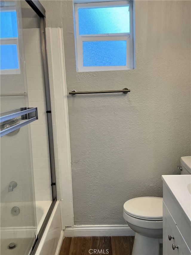 full bathroom featuring vanity, hardwood / wood-style flooring, bath / shower combo with glass door, and toilet