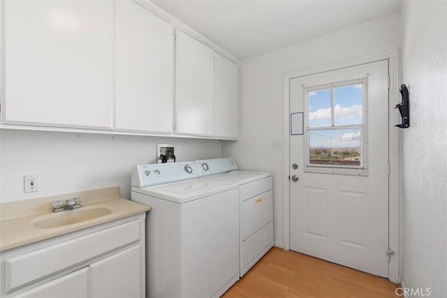 washroom featuring sink, light hardwood / wood-style flooring, cabinets, and independent washer and dryer