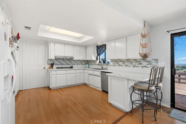 kitchen featuring a kitchen bar, light wood-type flooring, white cabinetry, and stainless steel dishwasher