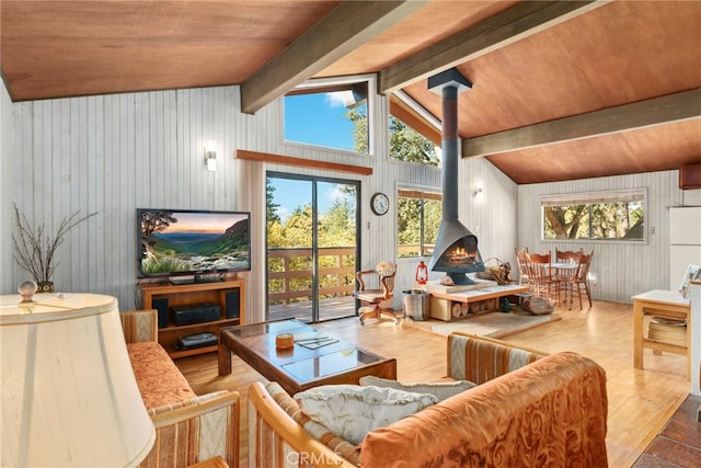 living room featuring a wood stove, vaulted ceiling with beams, wooden walls, wood ceiling, and hardwood / wood-style flooring