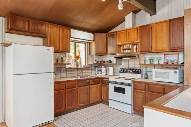 kitchen with wood walls, white appliances, backsplash, sink, and vaulted ceiling