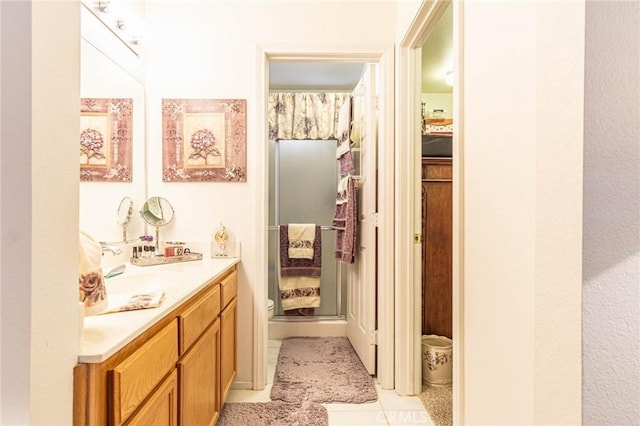 bathroom featuring toilet, vanity, tile patterned floors, and a shower with shower door