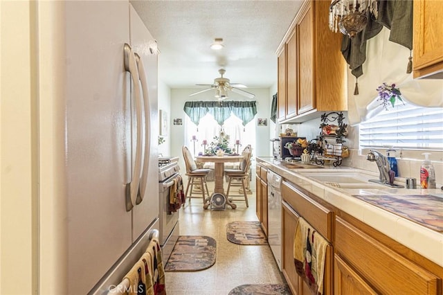 kitchen featuring appliances with stainless steel finishes, tile countertops, ceiling fan, and sink