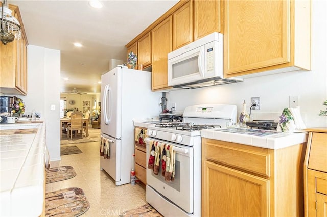 kitchen with light tile patterned floors, white appliances, tile countertops, and ceiling fan