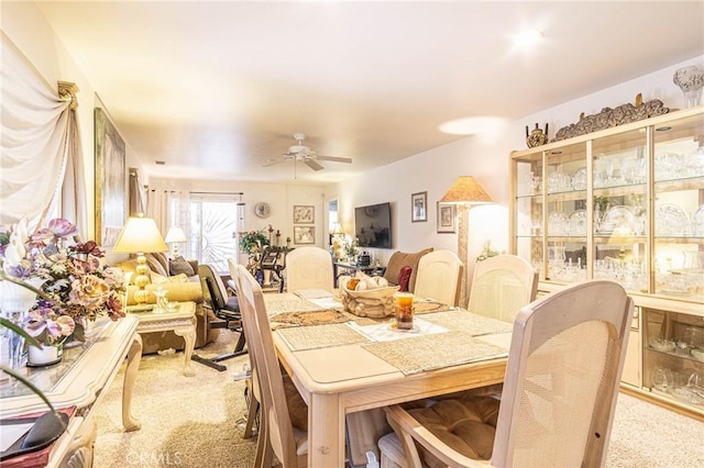 carpeted dining area with ceiling fan