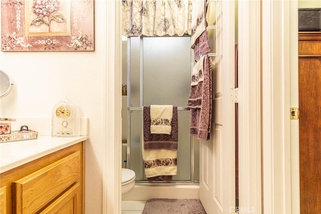 bathroom with vanity, a shower with shower door, and toilet