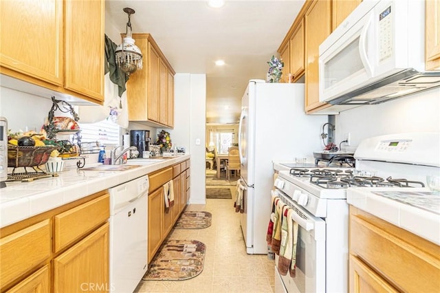 kitchen with a wealth of natural light, white appliances, light tile patterned floors, and tile counters