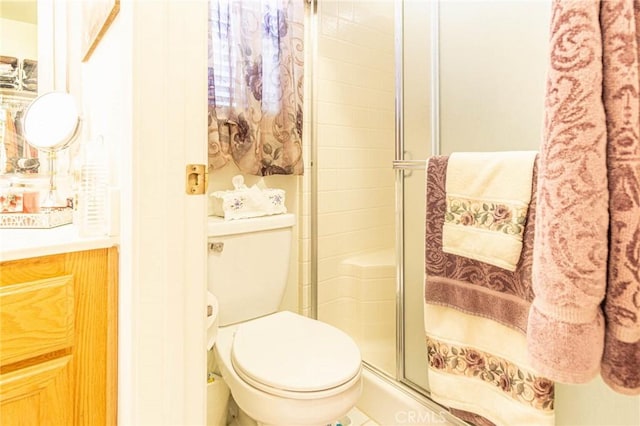 bathroom featuring vanity, toilet, and an enclosed shower