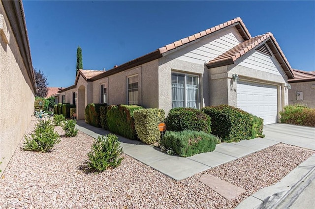 19046 Stoddard Way, Apple Valley, CA 92308 - view of side of property with an attached garage, a tiled roof, stucco siding, and concrete driveway