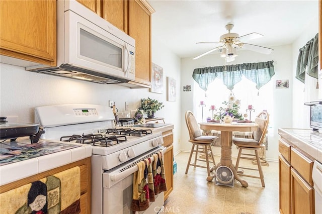 kitchen featuring tile countertops, ceiling fan, and white appliances