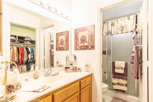 bathroom featuring tile patterned flooring, vanity, toilet, and an enclosed shower